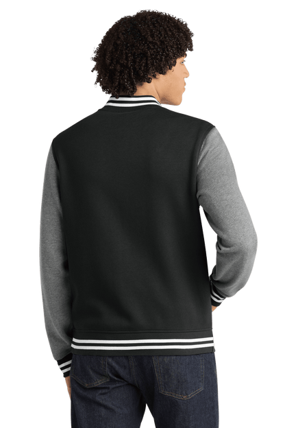 Black Sport-Tek varsity jacket with vintage heather fabric, featuring classic striped cuffs and collar, customizable or plain style.