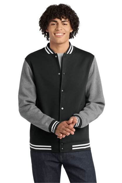 Black Sport-Tek varsity jacket with vintage heather fabric, featuring classic striped cuffs and collar, customizable or plain design.