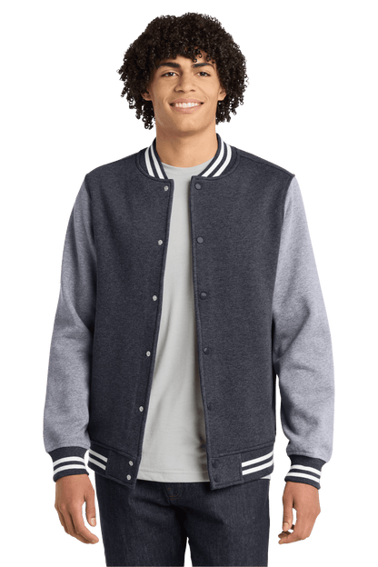 Graphite Heather varsity jacket by Sport-Tek with contrasting sleeves, front pockets, and ribbed cuffs, shown in print view.