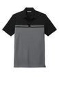 Men's TravisMathew Sunset Blocked Polo in black and dark grey Heather, showing a flat front view of the stylish men's polo shirt.
